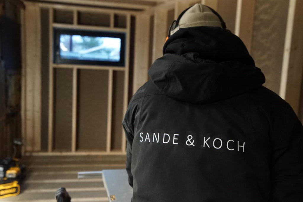 Tømrer fra Sande & Koch i arbeid inne i et nybygg under oppføring
